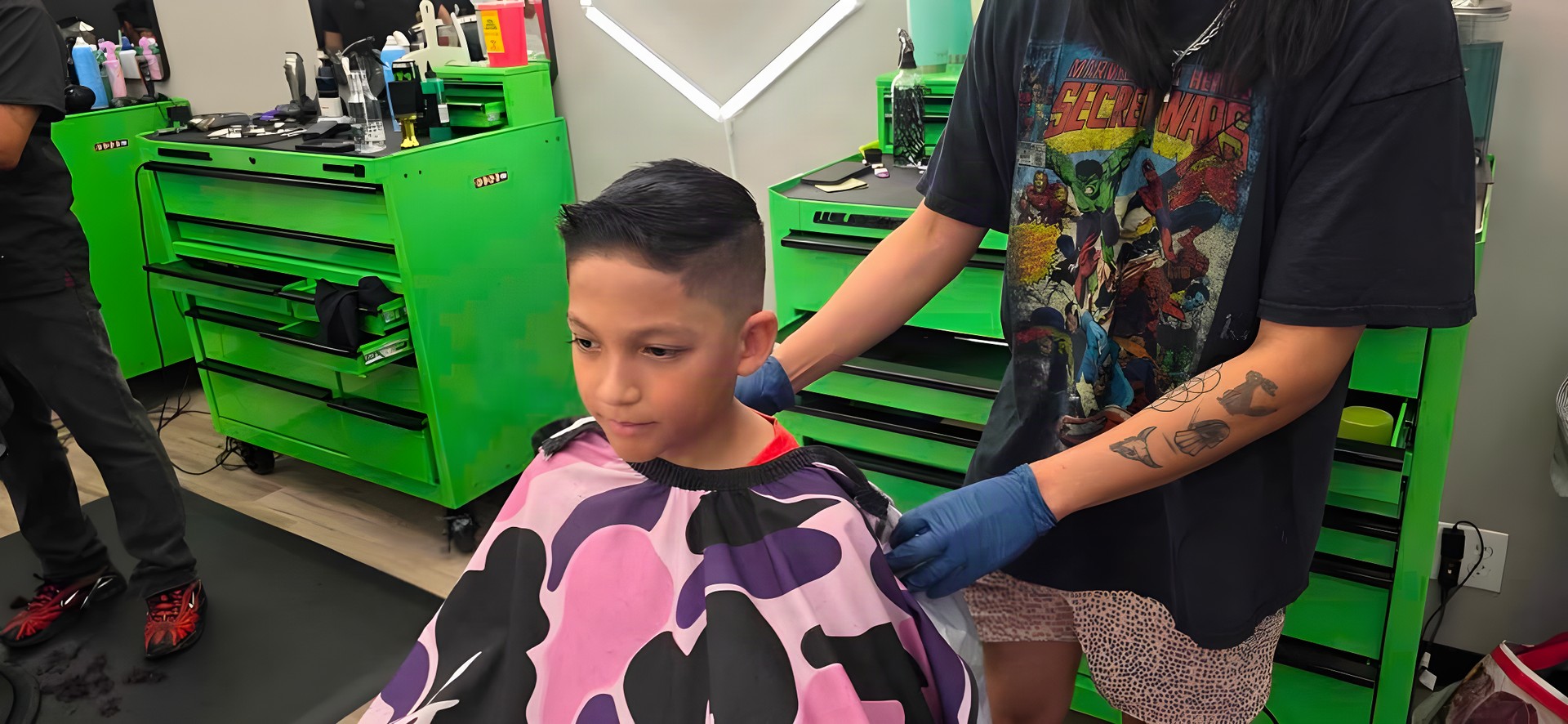 A barber cutting a young client's hair at a Fade Lab station